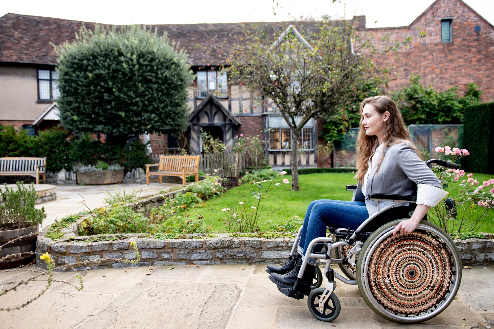 A wheelchair user guest uses a path outside an elizabethan house and garden