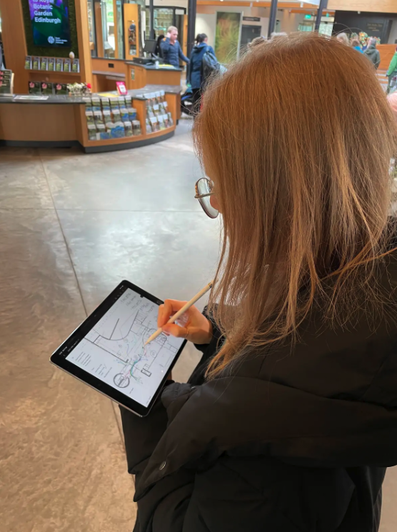 A member of the Mima team stands near the front desk, using a tablet to observe and map how visitors move through the space and their behaviour patterns and typical journeys.