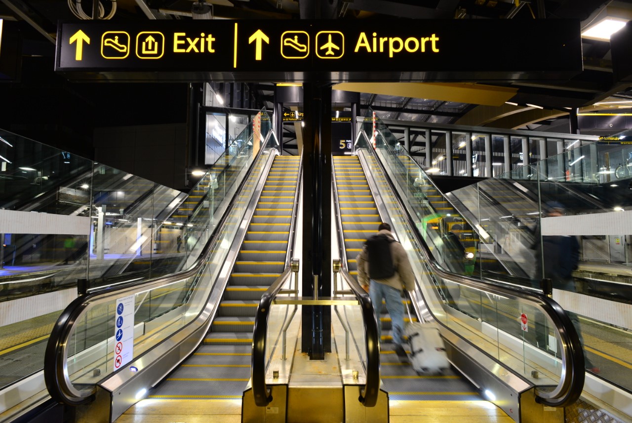 A photo of the finished Gatwick airport station showing the escalator with clear signage icons