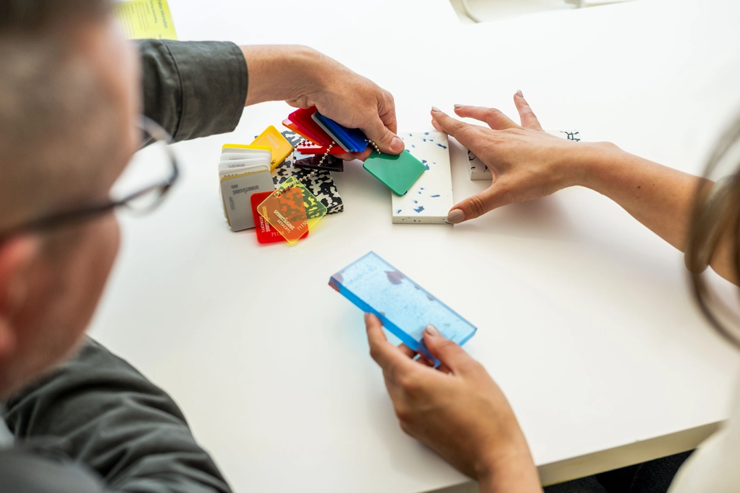 Two people looking at swatch samples of different textures and colours against a white table